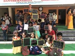 Students holding up their chalkboards outside the school