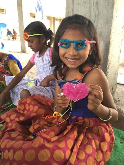 A student wearing craft glasses and holding a paper heart